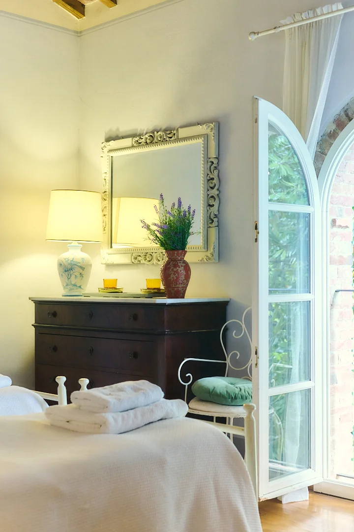 Antique dresser and arched window in a Villa Niccolai bedroom