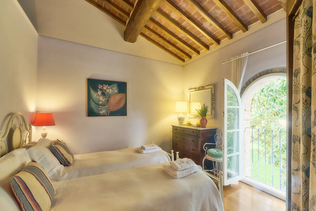 Twin bedroom with exposed Tuscan beams at Villa Niccolai