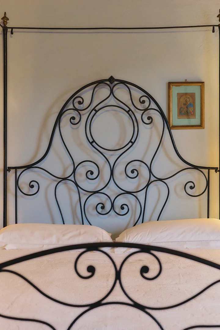 Historic bedroom with a wrought-iron bed at Villa Niccolai